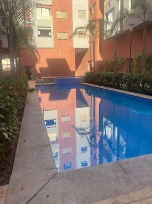 a reflection of a building in a swimming pool at Appartement de luxe avec piscine in Marrakech