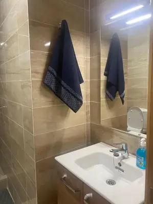 a bathroom with a sink and towels hanging on the wall at Appartement de luxe avec piscine in Marrakech