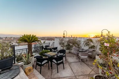 a patio with tables and chairs on a balcony at Riad Jebly - Exclusive -Jacuzzi & Breakfast ,10 min walk Jemaa El Fnaa - Panoramic View Rooftop in Marrakech