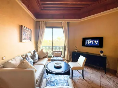 a living room with a couch and a tv at Oasis Palmeraie - Piscines & terrasses in Marrakech