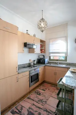 a kitchen with wooden cabinets and a stove top oven at Marrakech Palmeraie 3, 2-bedroom appartement, ,res with pool in Marrakech