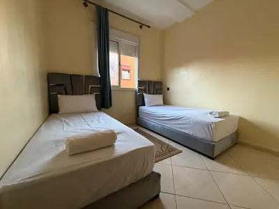 two beds in a room with a window at Calm & Comfortable Appartement Close to Airport in Marrakech