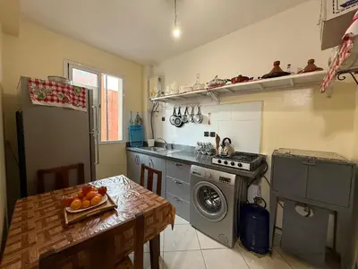 a kitchen with a washing machine and a table with a bowl of fruit at Calm & Comfortable Appartement Close to Airport in Marrakech