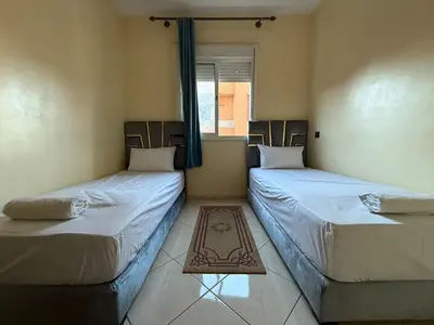 two twin beds in a room with a window at Calm & Comfortable Appartement Close to Airport in Marrakech