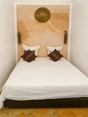 a bed with white sheets and brown pillows on it at Riad coup de coeur, Medina, Marrakech in Marrakech