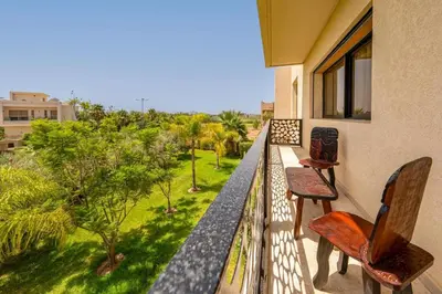 a balcony with two chairs and a view of a yard at Golf Resort 4BR Villa Heated Pool Free Pickup in Marrakech