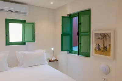 a bedroom with green windows and a white bed at Riad Dar 77 in der Medina mit Terrasse in Marrakech