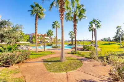 a park with palm trees and a swimming pool at Golf View Escape in Oulad Akkou