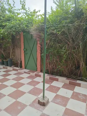 a green door on a checkered floor with a pole at Chambre dans un Maison traditionnel avec jardin système de riad dans une ambiance familiale marocain in Marrakech