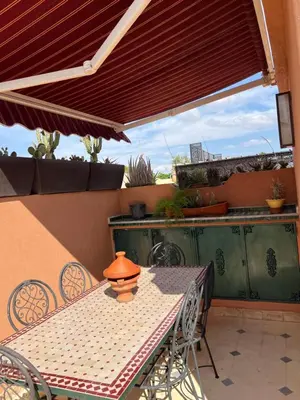 a table and chairs on a patio with a red roof at Riad Marhaba Kasbah in Marrakech