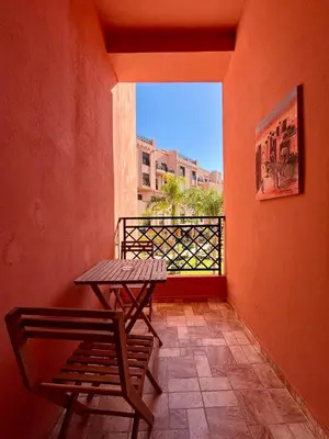 a table and a bench sitting on a balcony at Appart cosy & chic premium Village, 5 piscines in Marrakech