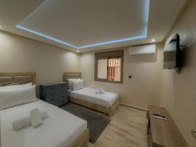 a room with two beds and a tv and a window at Essalmi Duplex Apartment in Marrakech in Marrakech