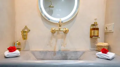 a bathroom with a sink and a mirror and towels at Riad Le Soleil Rouge in Marrakech