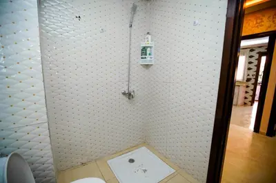 a bathroom with a white tiled wall with a toilet at Bel Appartement 2 Chambres Confort et Emplacement Idéal in Marrakech