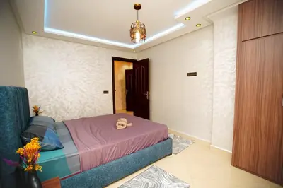 a bedroom with a bed and a chandelier at Bel Appartement 2 Chambres Confort et Emplacement Idéal in Marrakech
