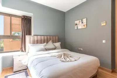 a bedroom with a large bed with white sheets and a window at Luxury Villa Private Pool & Golf View 7 min to center in Marrakech