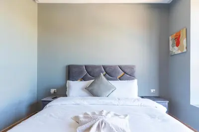 a bedroom with a large white bed with a gray headboard at Luxury Villa Private Pool & Golf View 7 min to center in Marrakech