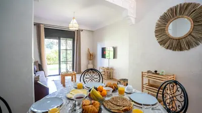 a dining room with a table with food on it at Appartement cosy, calme, détente, piscines, jardins in Marrakech