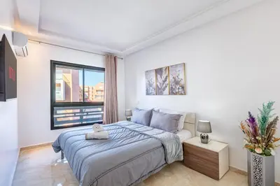a white bedroom with a bed and a window at Appartement Chic & Cosy Hivernage in Marrakech