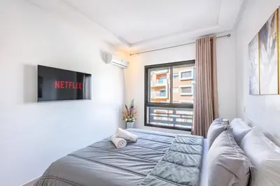 a bedroom with a bed and a tv on a wall at Appartement Chic & Cosy Hivernage in Marrakech