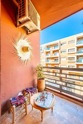 a balcony with two chairs and a table and a building at Appartement Chic & Cosy Hivernage in Marrakech