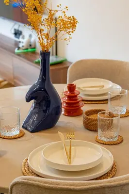 a table with plates and a blue vase with flowers at Modern 1BR , Cinema & Xbox , Central Guéliz in Marrakech