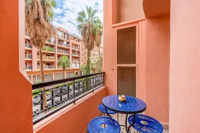 a table on a balcony with a view of a building at Modern 1BR , Cinema & Xbox , Central Guéliz in Marrakech