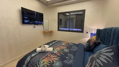 a bedroom with a bed and a window and a tv at Appartement 3 chambres jaccuzi in Marrakech