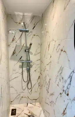 a bathroom with a shower with white marble walls at Madame plaza in Marrakech