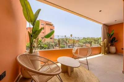 a balcony with two chairs and a table and a large window at Guéliz Centre Haut Standing in Marrakech