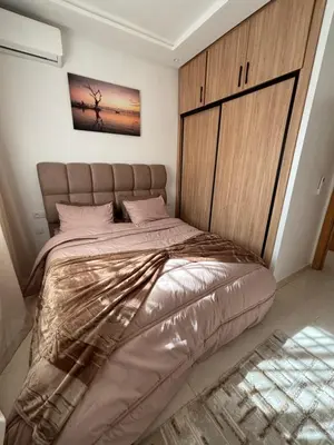 a bedroom with a large bed with a wooden headboard at Appartement Targa Marrakech in Marrakech