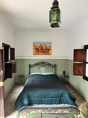 a bedroom with a bed with a green comforter at Riad Dar Aïlen Medina in Marrakech