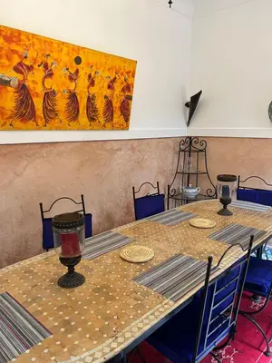 a table with chairs and a painting on the wall at Riad Dar Aïlen Medina in Marrakech