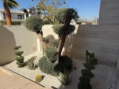 a garden with trees and plants in front of a wall at Villa Alfa Élégance, Calme & Confort Premium in Marrakech