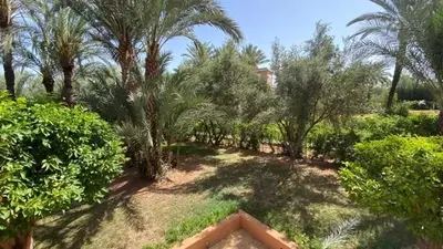 a garden with palm trees and bushes and a building at Grand duplex Palmeraie in Marrakech