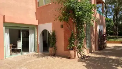 a pink building with a tree next to a patio at Grand duplex Palmeraie in Marrakech