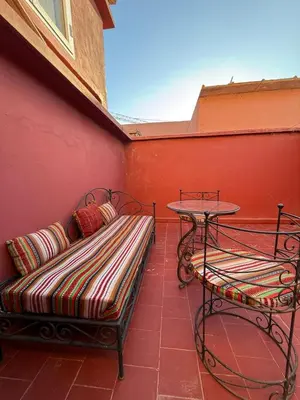 a bench and a table on a red wall at Riad Souleimane Résidence Qaria Siyahiya in Marrakech