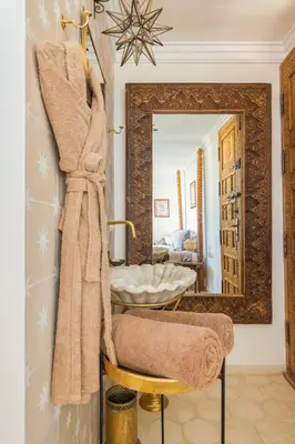 a bathroom with a mirror and a chair with a towel at Riad Koubba in Marrakech