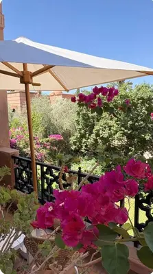 a garden with pink flowers and an umbrella at Welcome to your Stylish Atlas View Apartment in Marrakech