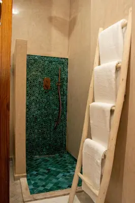a shower in a bathroom with a green glass wall at Riad EL Mouloudi in Marrakech