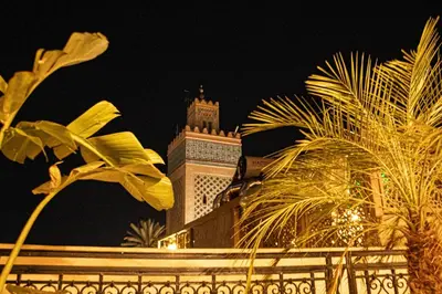 a tall building with a clock tower at night at Riad EL Mouloudi in Marrakech