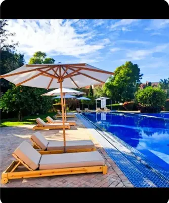 a group of lounge chairs with an umbrella next to a swimming pool at Oasis Garden Apartment Marrakech in Marrakech