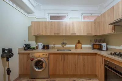 a kitchen with wooden cabinets and a washing machine at Princess Gueliz center, Comfort, Quiet and View in Oulad Akkou