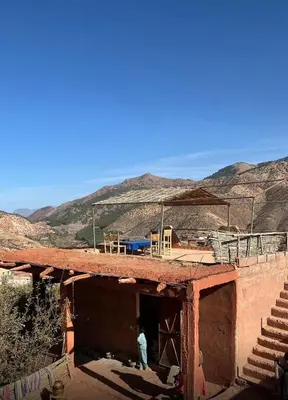 a person standing outside of a building with mountains in the background at Atlas Mountains 3 Valleys Experience All-Inclusive Private Tour from Marrakesh in Marrakech
