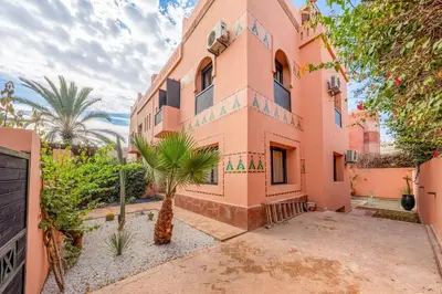 a pink building with palm trees in front of it at Luxury Beldi & Piscine at Villa Riad El Menzeh in Marrakech