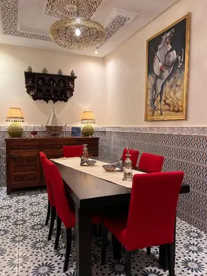 a dining room with a table and red chairs at Riad DAR BARBI in Marrakech