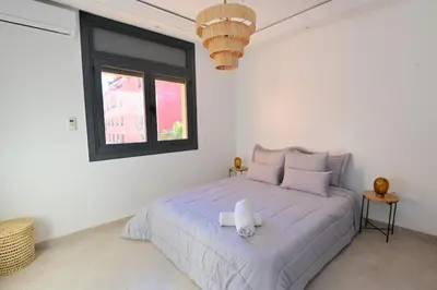 a white bedroom with a large bed with a window at Appartement spacieux de 3 chambres à gueliz in Marrakech