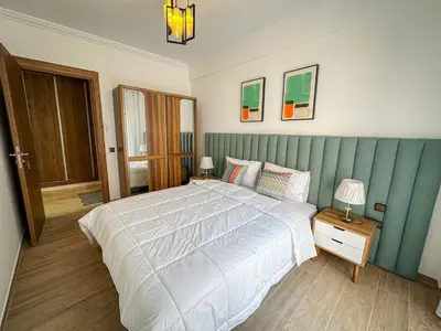 a bedroom with a large bed with a blue headboard at Well equipped luxury apartment in centre marrakech ctm aeroport train medina in Marrakech