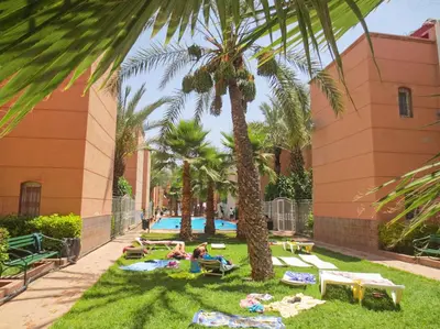 a group of people laying on the grass near a swimming pool at appartement en résidence in Marrakech