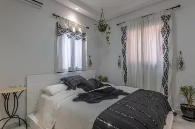 a white bedroom with a bed with black pillows at Dar Choway in Marrakech